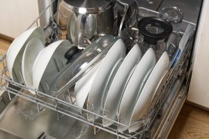 An open dishwasher is filled to the brim with clean dishes and pots.